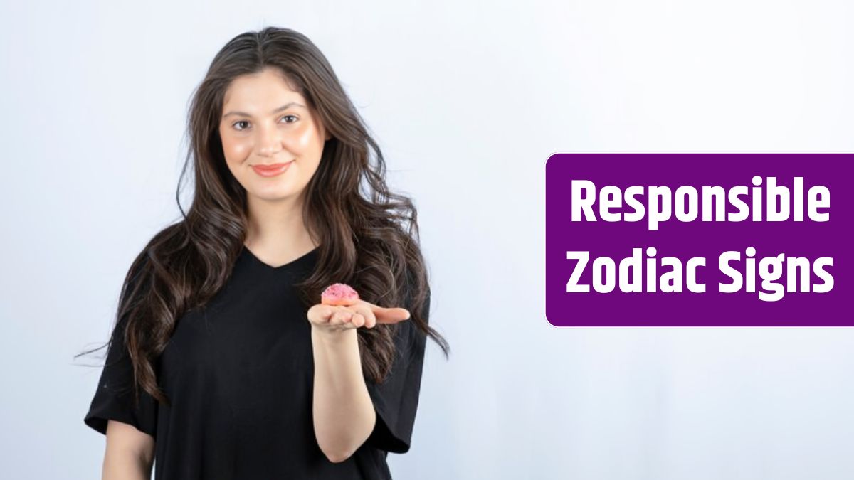 Young girl in black outfit holding pink cookie on white wall.